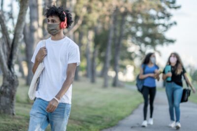 students walking on college campus while wearing masks