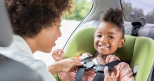 car seat with mother buckling in young daughter