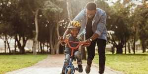 father teaching son to ride a bike