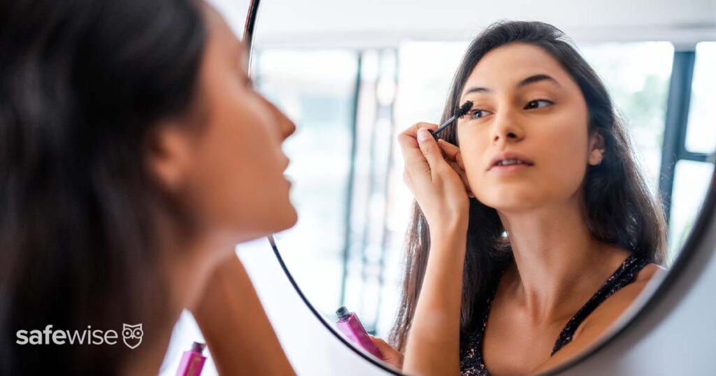 woman applying mascara in mirror