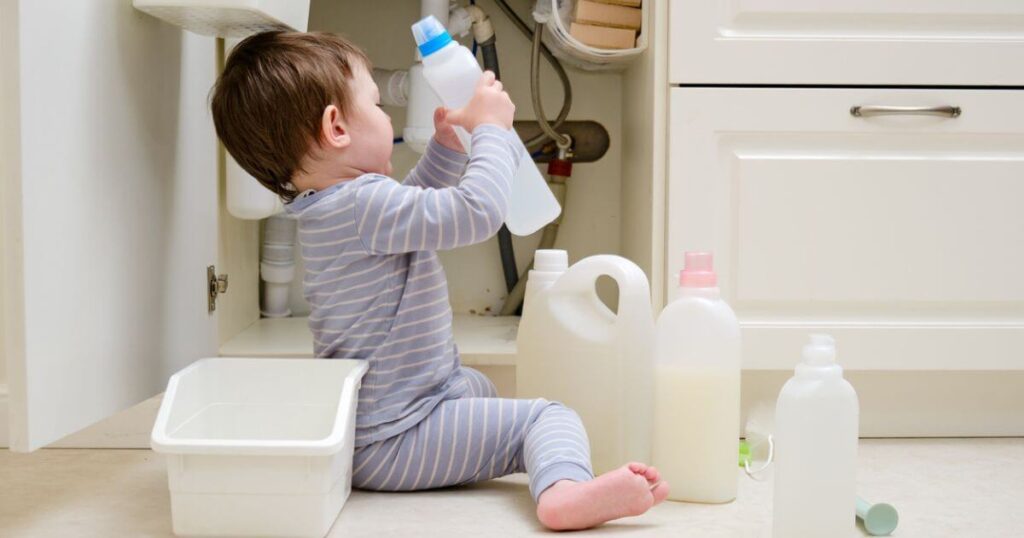 A child is playing with chemical cleaning products under the sink in the kitchen: