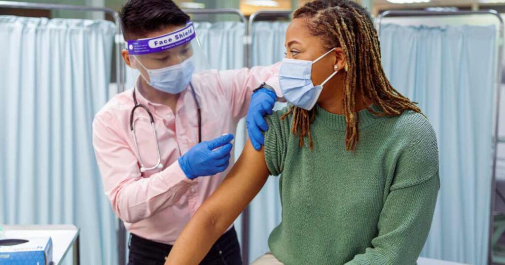 Black woman receiving COVID-19 vaccination injection stock photo