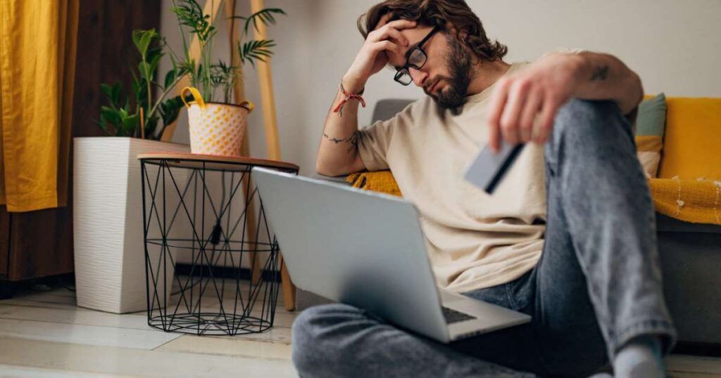 A worried man holds his head because he can't figure out what's wrong with his credit card stock photo