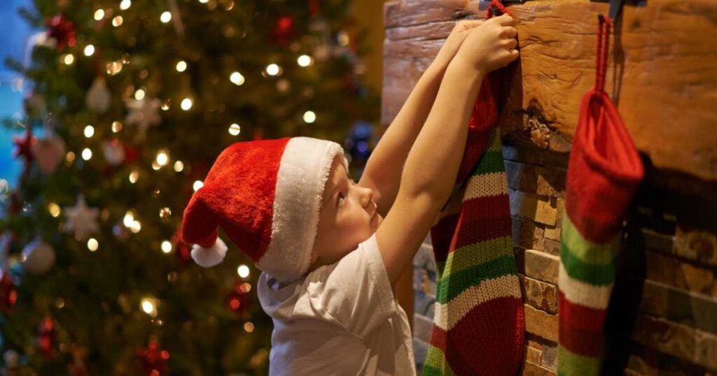 Shot of a little boy hanging up Christmas stocking at home