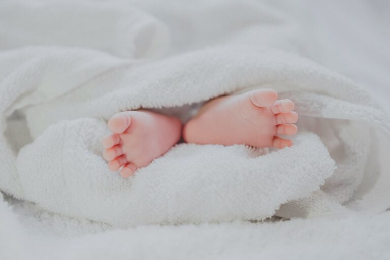 Baby feet poking through white towel. Photo by Fe Ngo on Unsplash