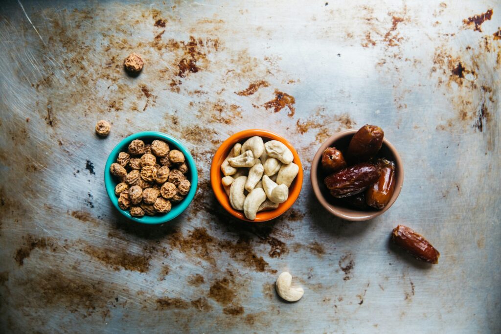 Three bowls with dates, cashews and another brown nut. Photo by Rachael Gorjestani on Unsplash