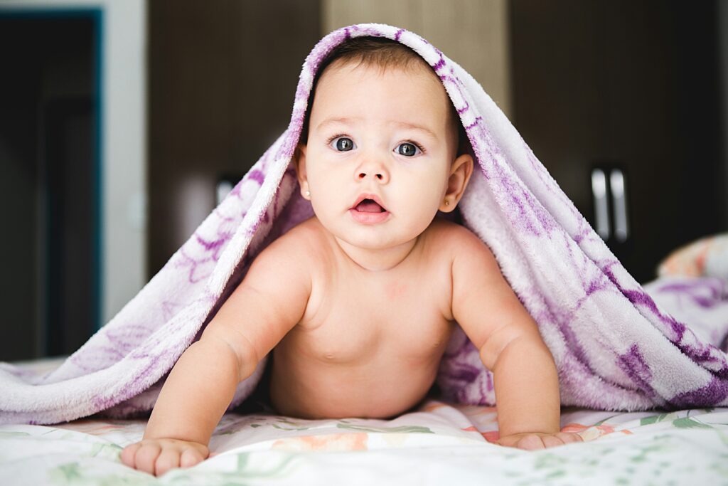 a baby on their tummy pushing up with a purple towel around their head