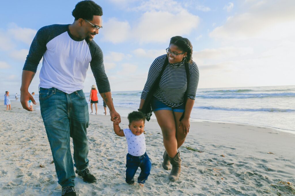 Family on beach teaching a baby how to walk