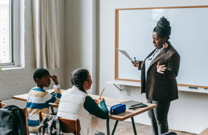 Kids at school talking to teacher.