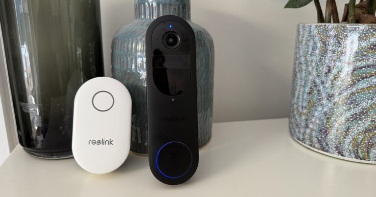 The Reolink Doorbell Battery and Reolink Chime on a white table, standing against two tall vases with a plant on the right.